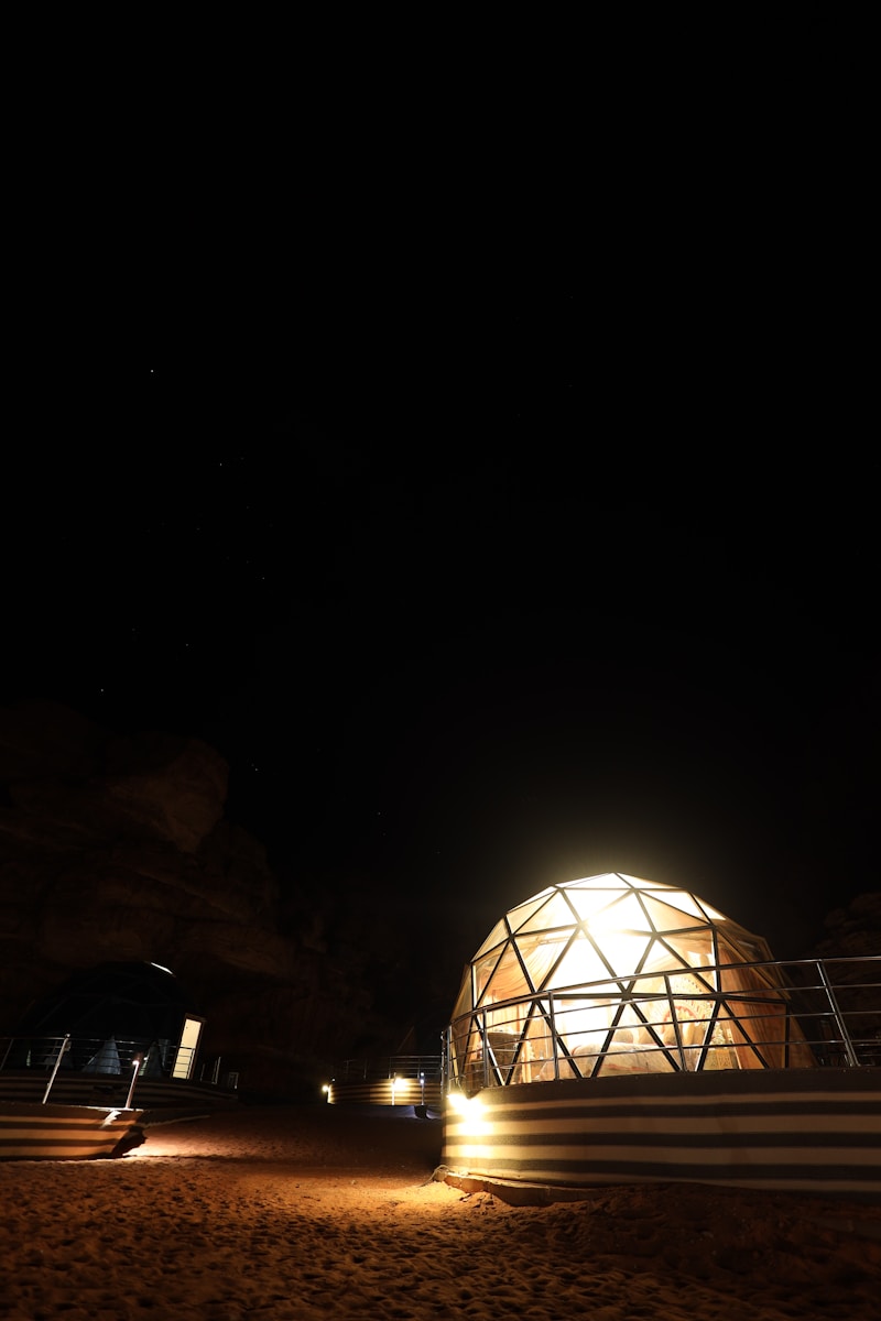 Illuminated geodesic dome at night under starry sky.
