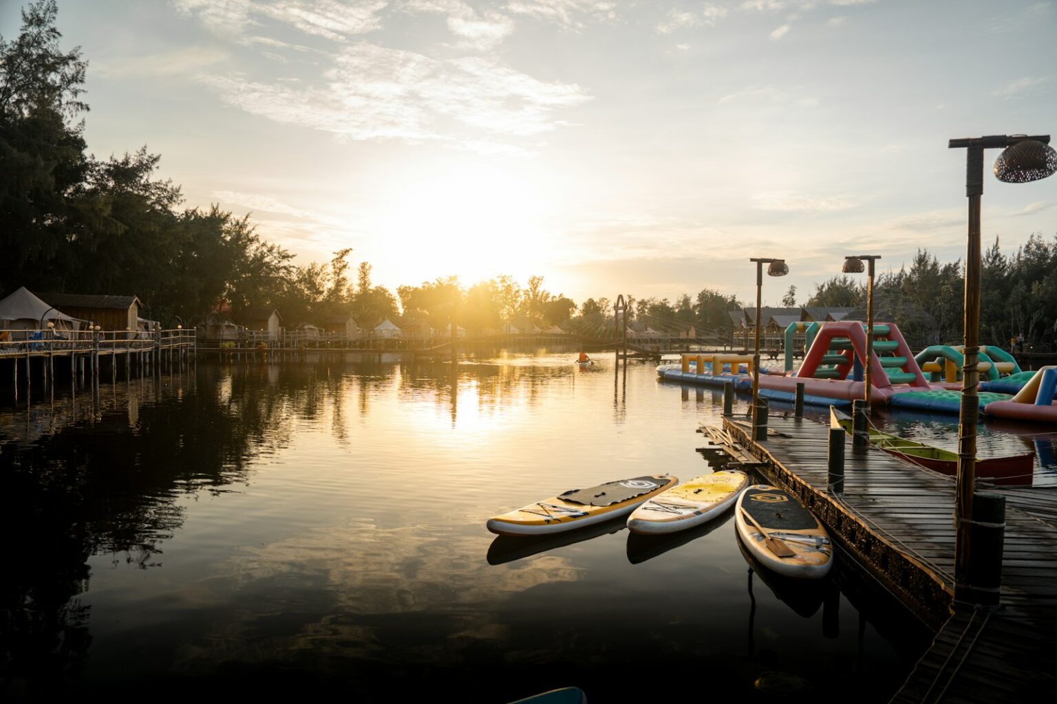 Sunrise bathes a lake with paddleboards and docks.